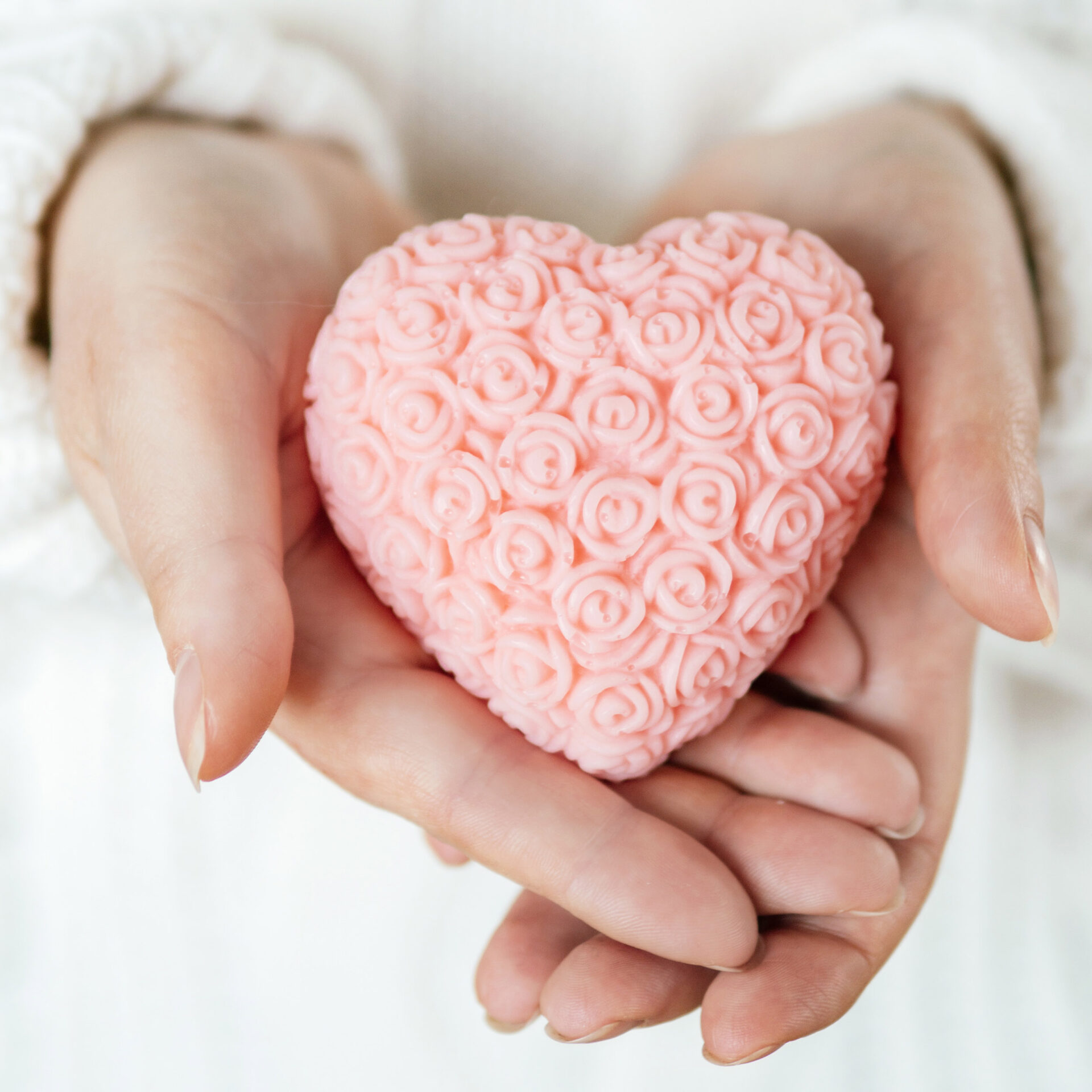 różowe mydełko glicerynowe w kształcie serca trzymane w dłoniach